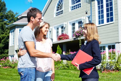 Realtor shaking hands with couple at house